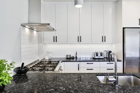 Dark kitchen benchtop with an inset sink and white cabinetry.