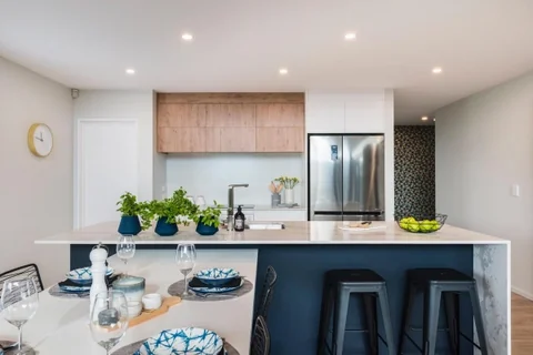 Dark kitchen island with timber cupboards, pendant lights and fresh flowers.