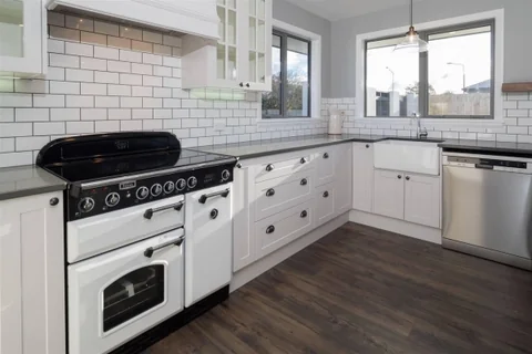 White kitchen with dark benchtops, a black range cooker and tiled splashback.