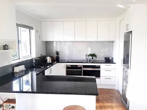 White kitchen with a dark wraparound benchtop and a black range cooker.