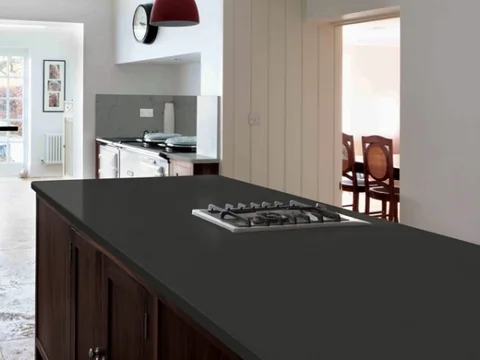 Dark island with a built-in cooktop and a timber feature wall.