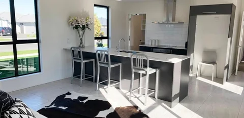 Open-plan kitchen and living room with a dark island and timber flooring.