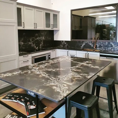 Grey veined benchtop with white shaker-style cabinets and bar stools.