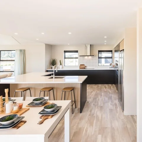 Light kitchen island with timber lower cabinetry in an open-plan space.