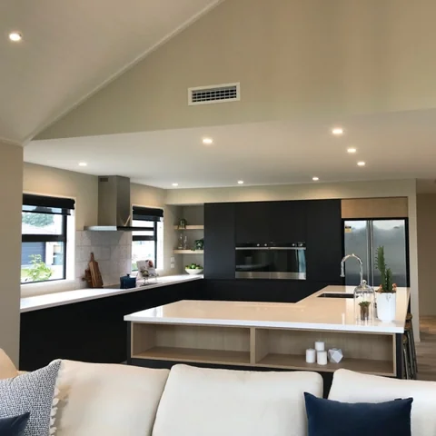 Open-plan living area with a dark kitchen wall and a light island.