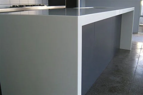 Detail of a pale waterfall benchtop over a grey kitchen island.