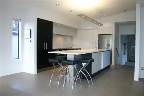 Open-plan white kitchen with a dark island base and a light benchtop.