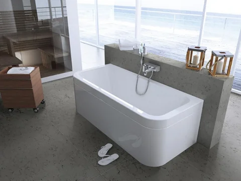 Freestanding bath and grey bathroom surfaces beside a bright window.